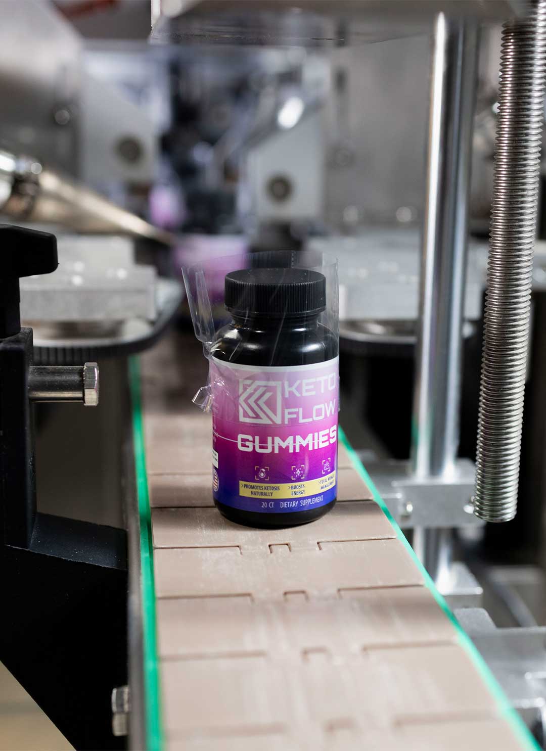 Gummy supplement bottle in shrink film on a bottling conveyor