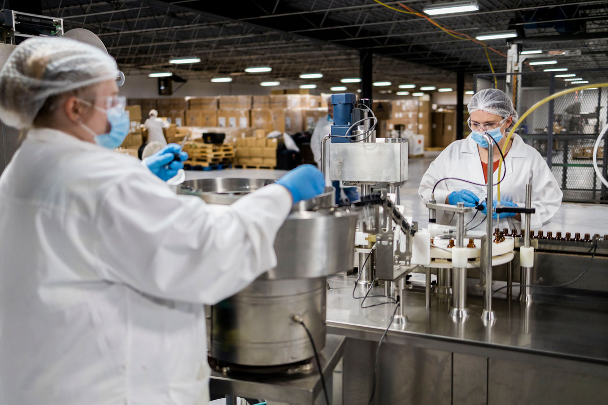 Two gowned technicians operating an amber-bottle filling line