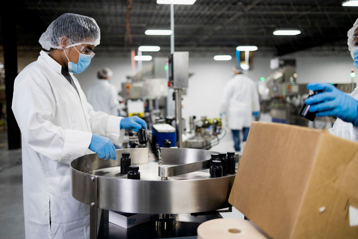 Technicians loading dark bottles onto a stainless rotary table