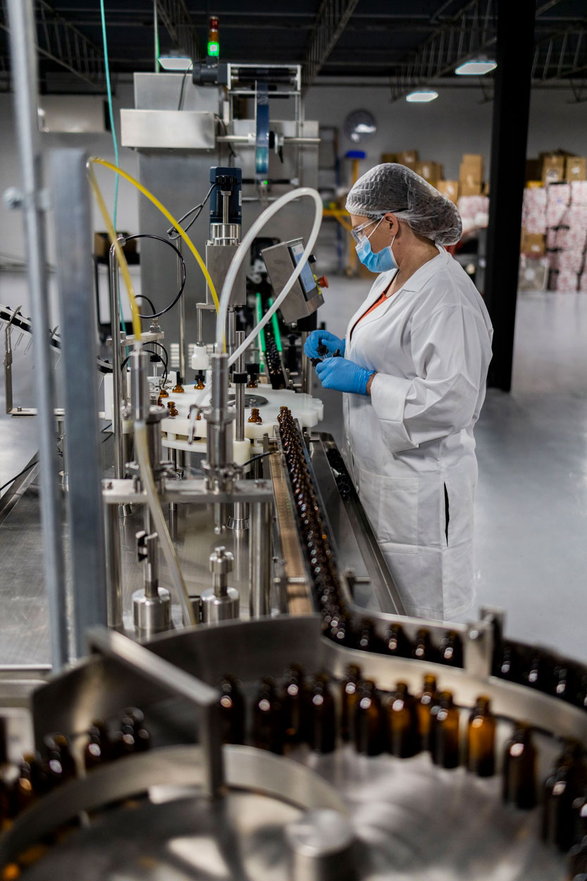 Technician monitoring amber bottles moving through a filling line